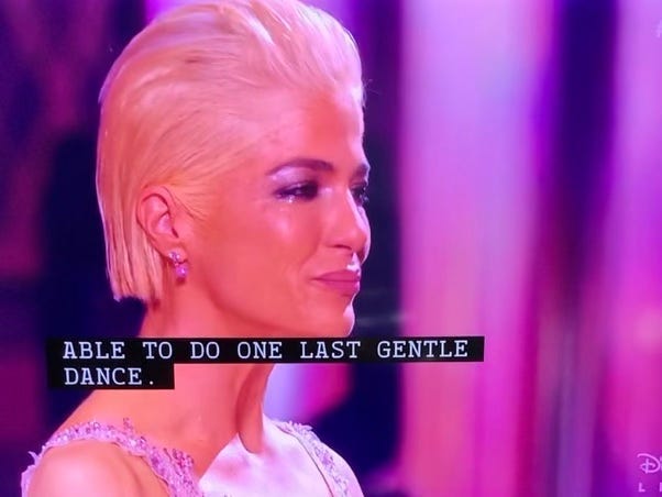 Selma Blair close up. Short bleached blonde hair slicked back, wearing makeup and an evening gown. The caption reads “Able to do one last gentle dance.” Selma Blair close up. Short bleached blonde hair slicked back, wearing makeup and an evening gown. The caption reads “Able to do one last gentle dance.”