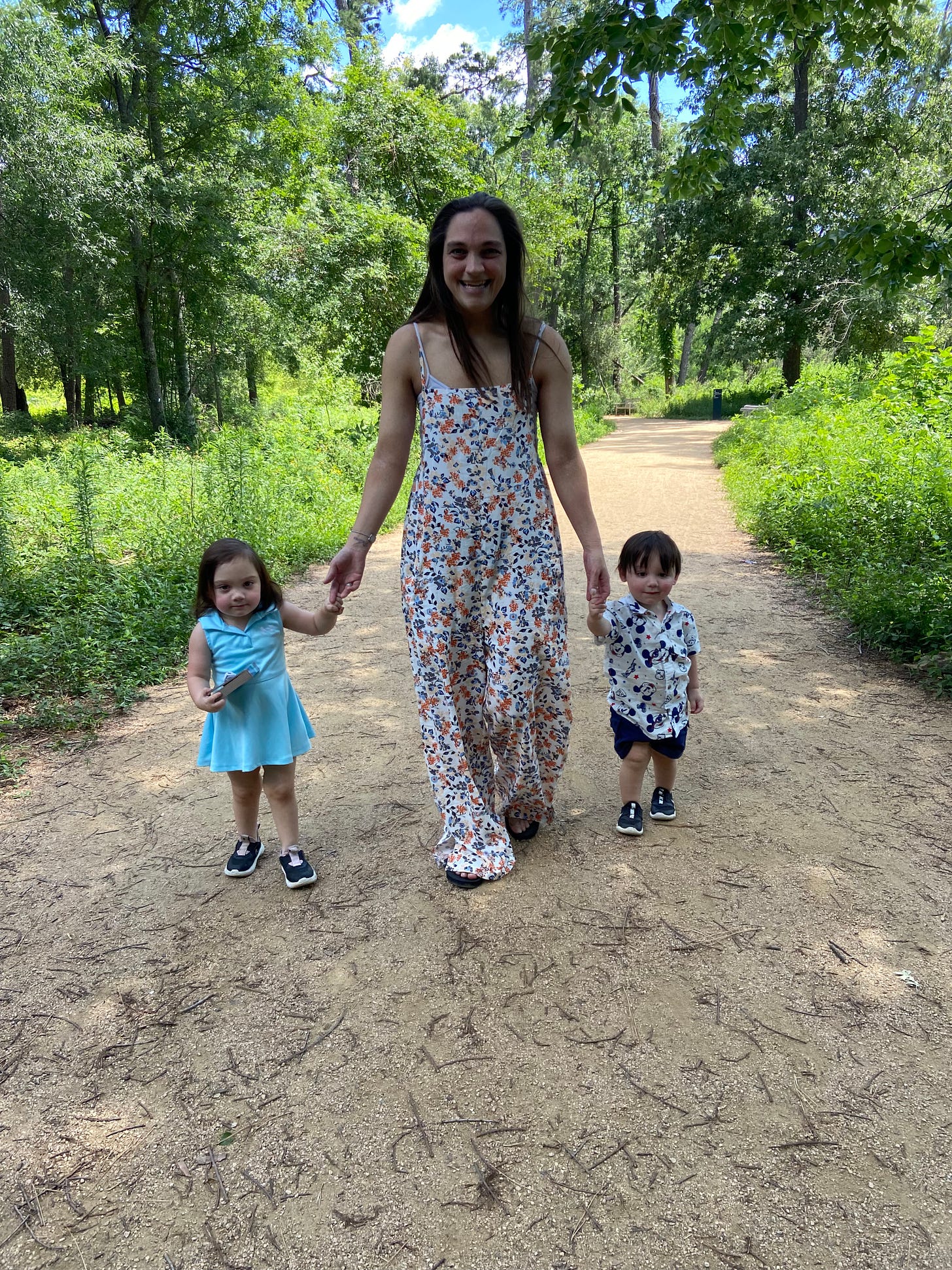 Mary and her children walking in nature, holding hands and smiling.