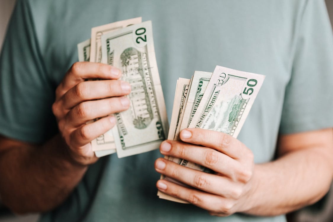 Free Close-up of a person counting US dollar bills indoors. Financial concept. Stock Photo