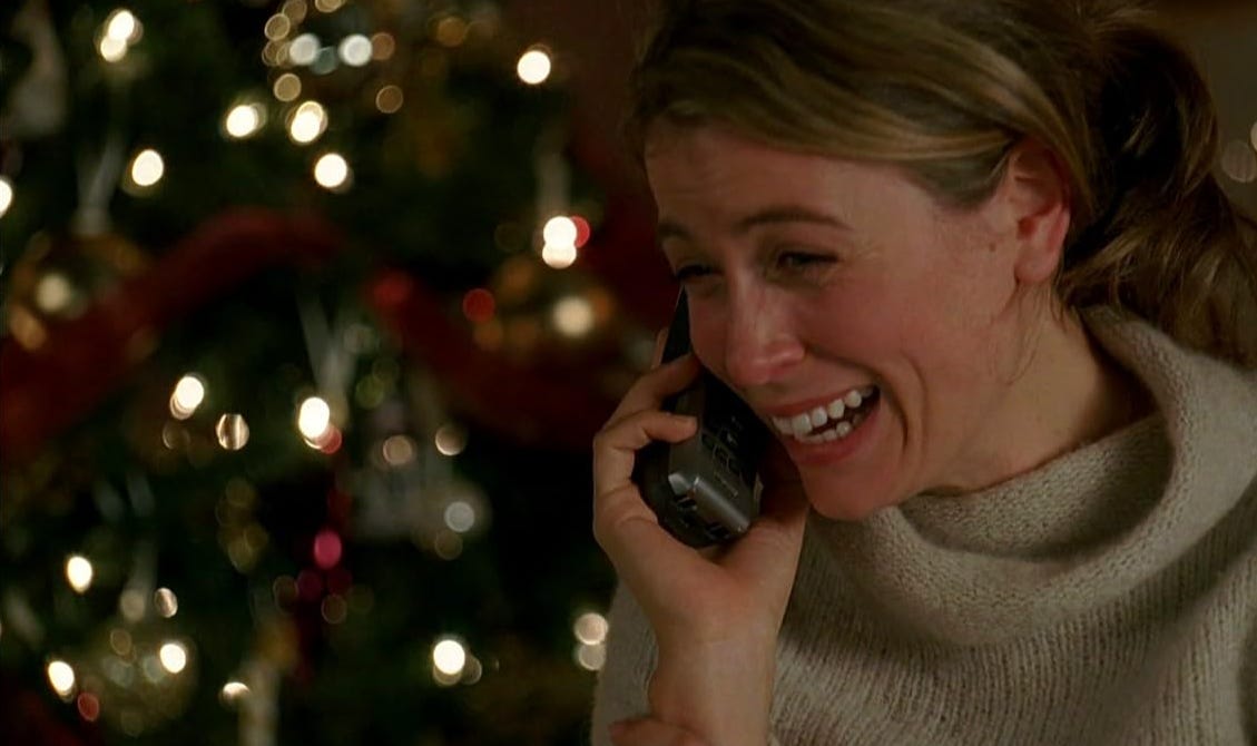 A scene from the tv show "Lost"; a woman stands in front of a Christmas tree crying happily into the phone