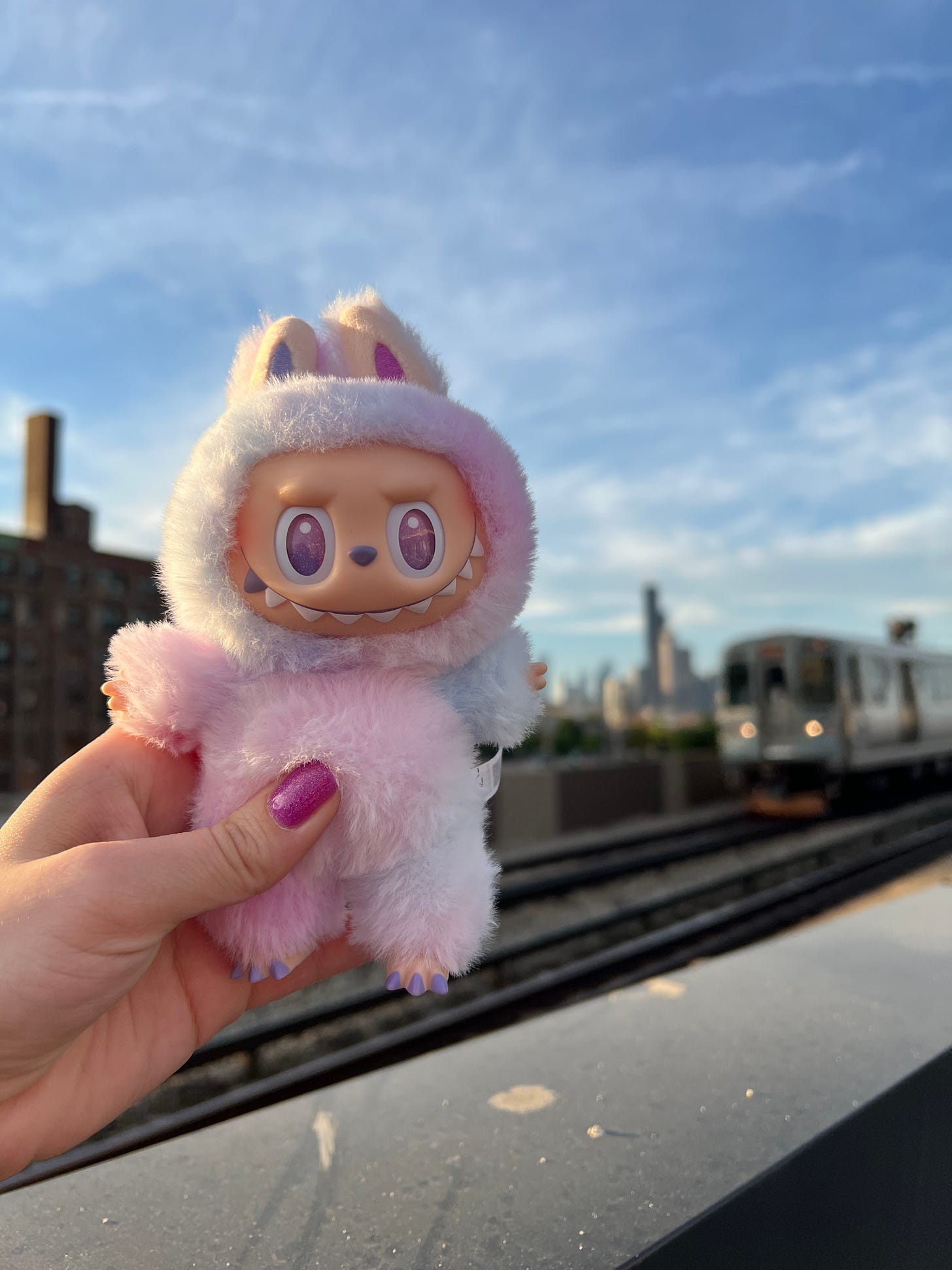 Labubu being held up in front of city skyline