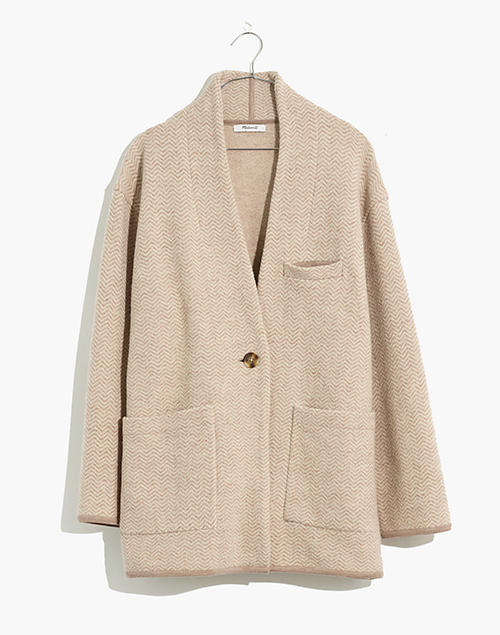 A chunky wool cardigan sweater with a shawl collar and single front button in cream-colored herringbone.