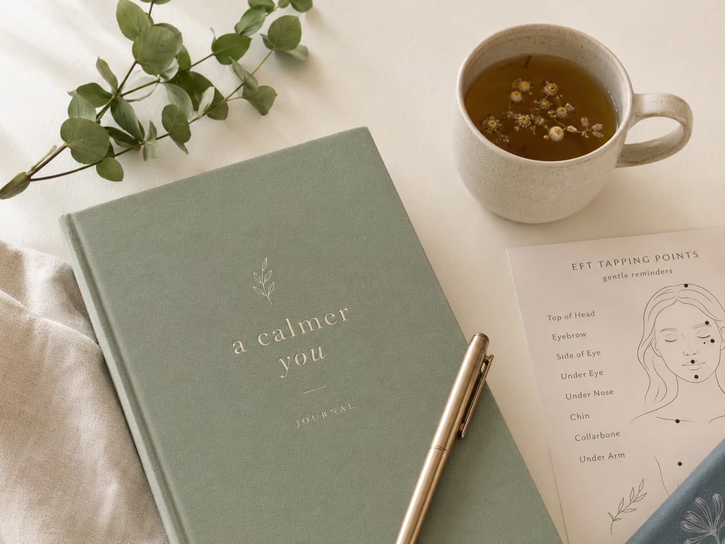 Notebook, tea, and EFT tapping notes on a calm desk for beginning a gentle self-tapping practice.