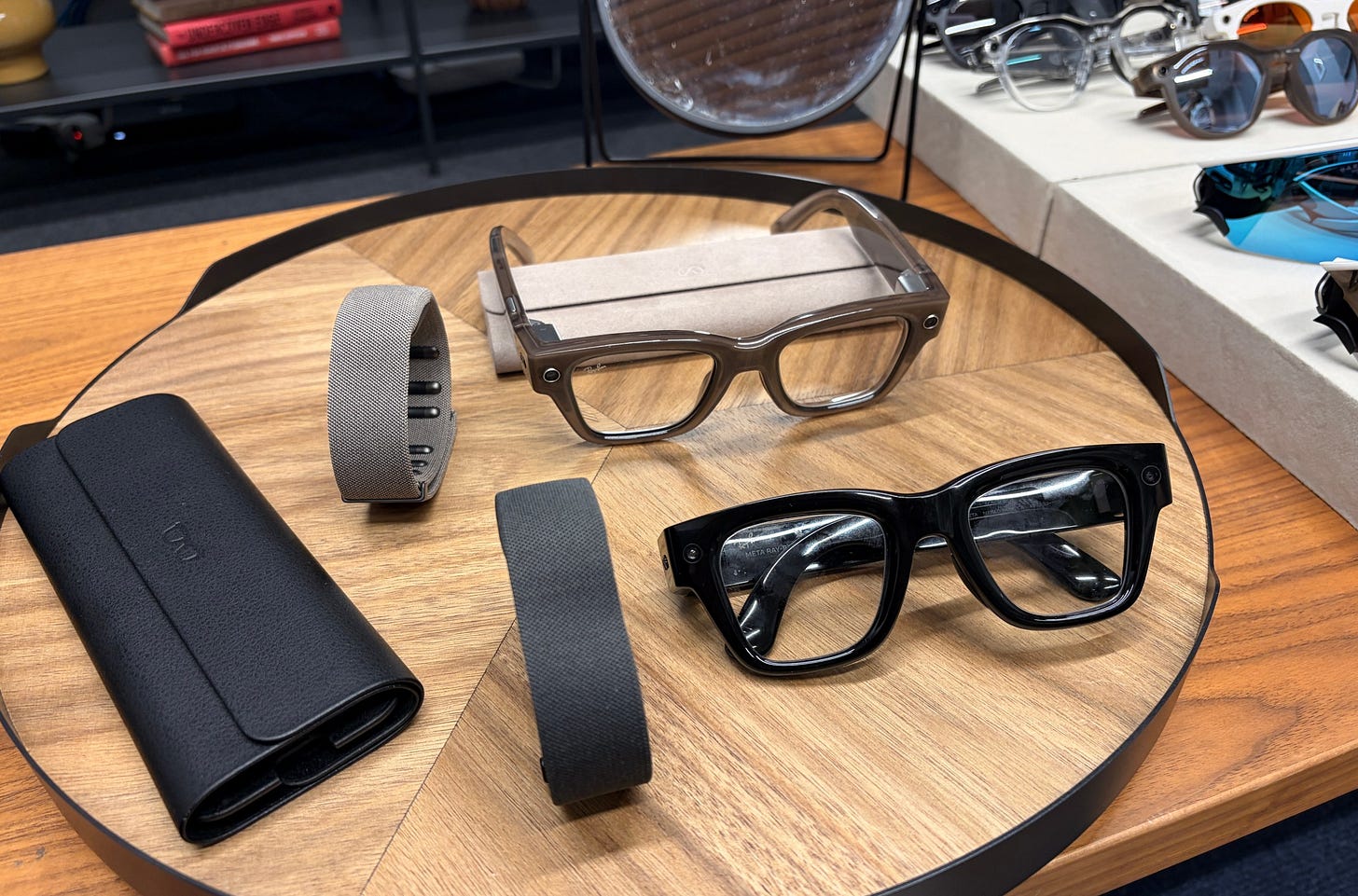 The Meta Ray-Ban Display in black and sand, with the accompanying neural wristbands and collapsible cases.
