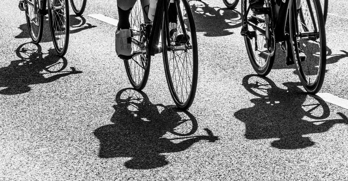 Photo: wal_ 172619 / Pexels Dynamic black and white image of cyclists casting shadows on the road during a group race.