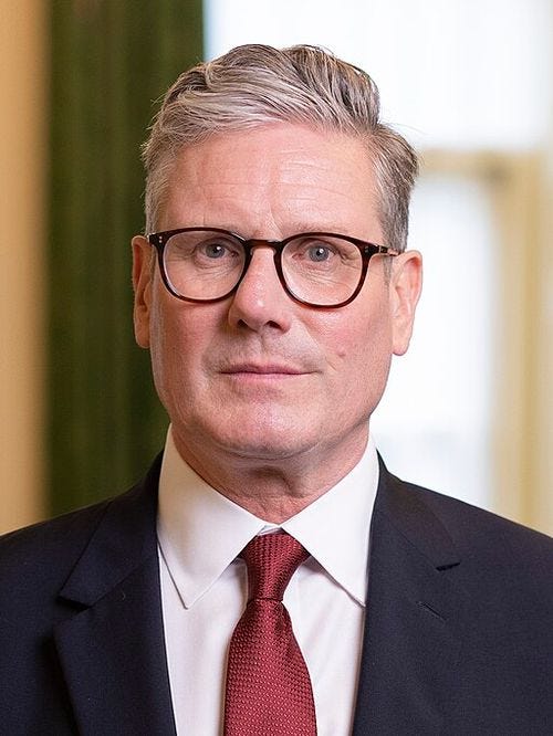 Head shot of Starmer wearing a dark suit jacket, white shirt, and red necktie
