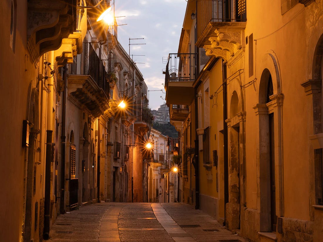 Streetlamps glowing along an empty limestone street in Ragusa Ibla at dusk. Streetlamps glowing along an empty limestone street in Ragusa Ibla at dusk.