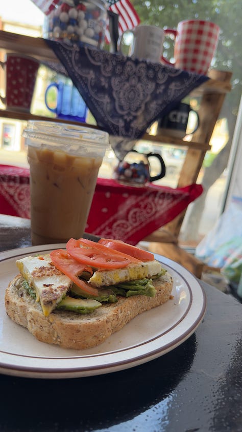 Flatlay of avocado toast with egg and tomato, an egg and bacon breakfast sandwich with a cup of red grapes, and an iced coffee. | A kid pointed to a game piece for an interactive board game. | Close up of the avocado toast on sourdough bread.