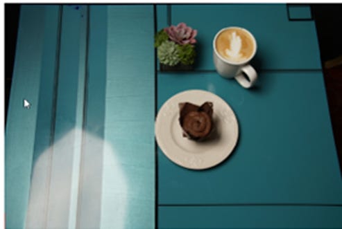 Coffee and muffin on a table, overshadowed by poor lighting and unflattering angles.
