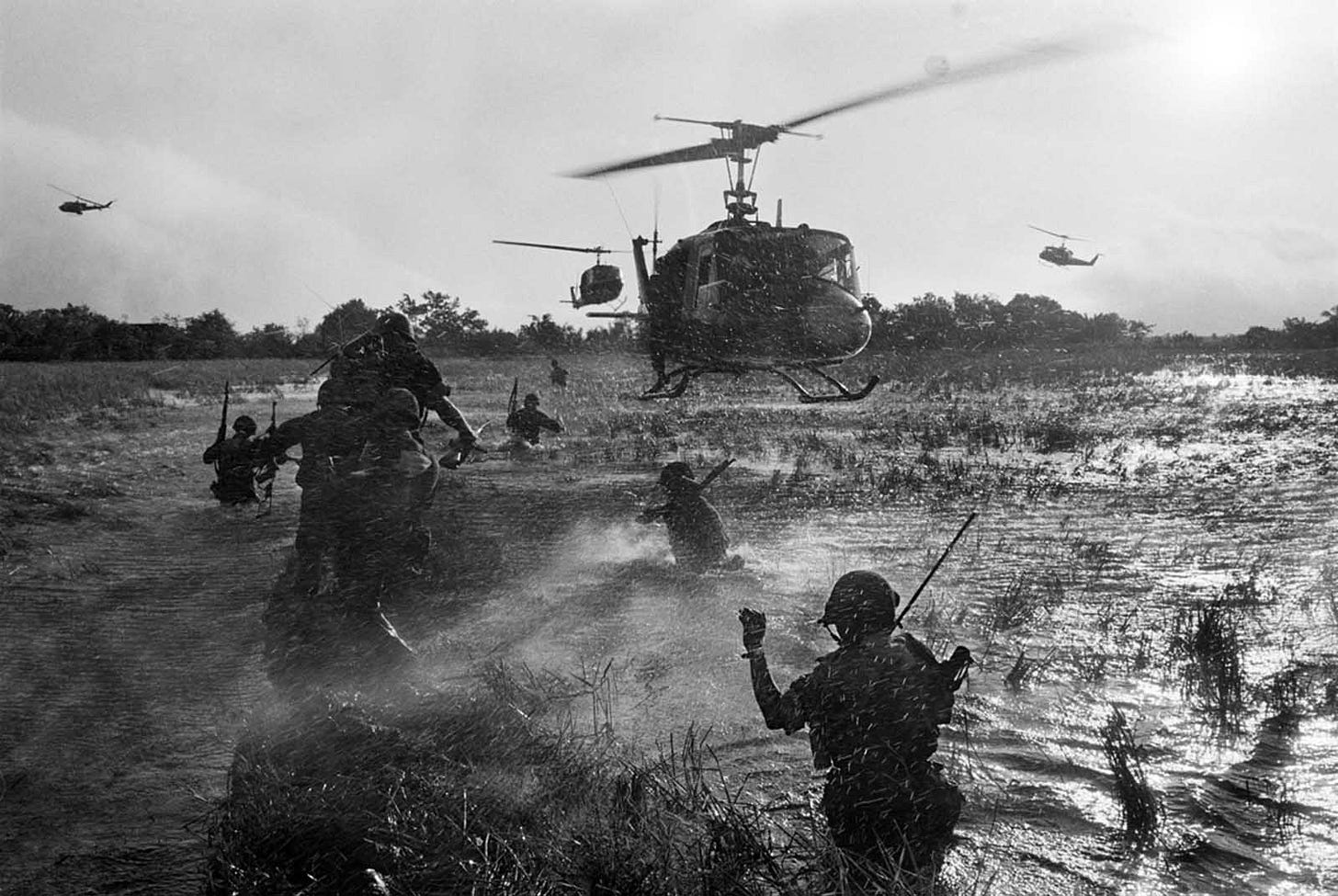 South Vietnamese troops navigate a flooded rice paddy in Long An province during an operation against Viet Cong guerrillas in the Mekong Delta, December 1964, supported by U.S. 'Eagle Flight' helicopters deploying airborne reinforcements. South Vietnamese troops navigate a flooded rice paddy in Long An province during an operation against Viet Cong guerrillas in the Mekong Delta, December 1964, supported by U.S. 'Eagle Flight' helicopters deploying airborne reinforcements.