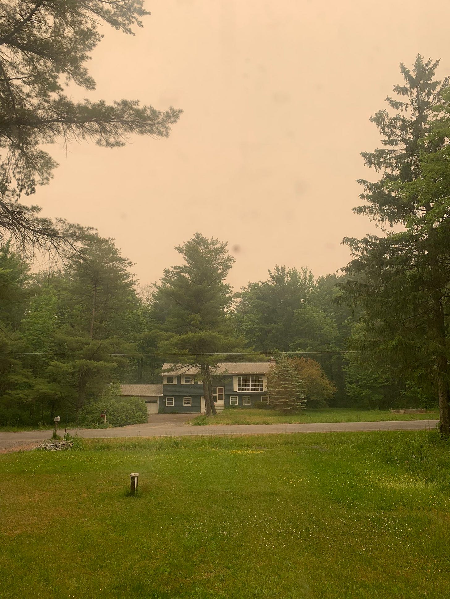 View out of my window of the house across the street. The sky above it is a smoky orange color