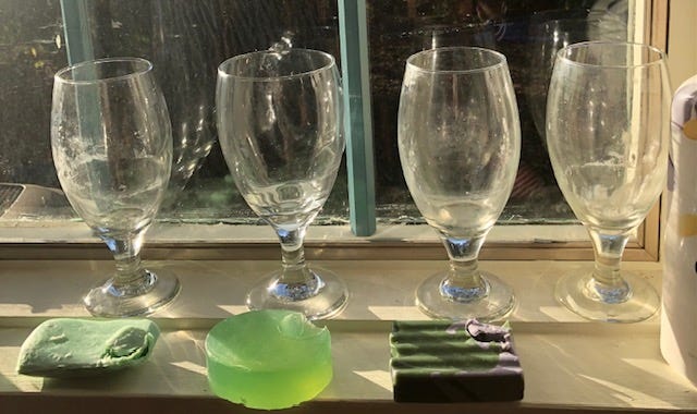 A row of wine glasses on a window sill

Description automatically generated