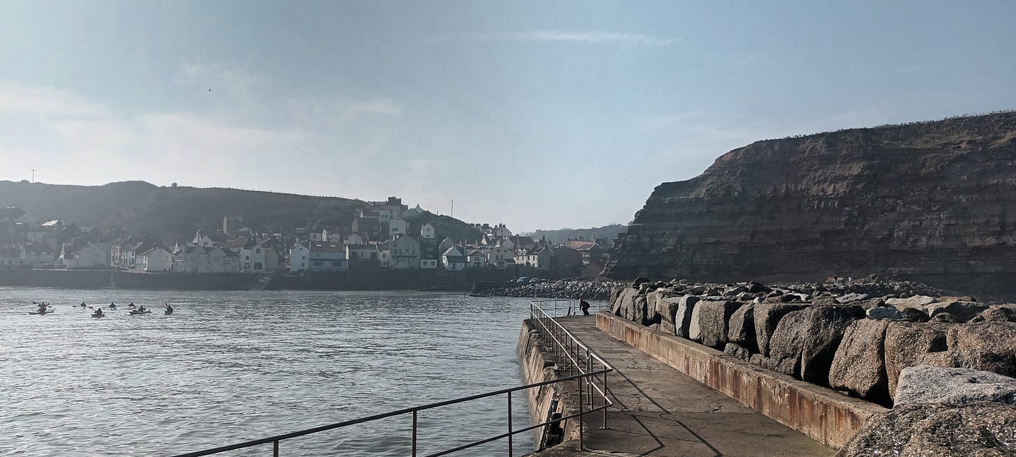 View of the fishing village of Staithes from the Harbour Arm and there are a group of kayakers in the water