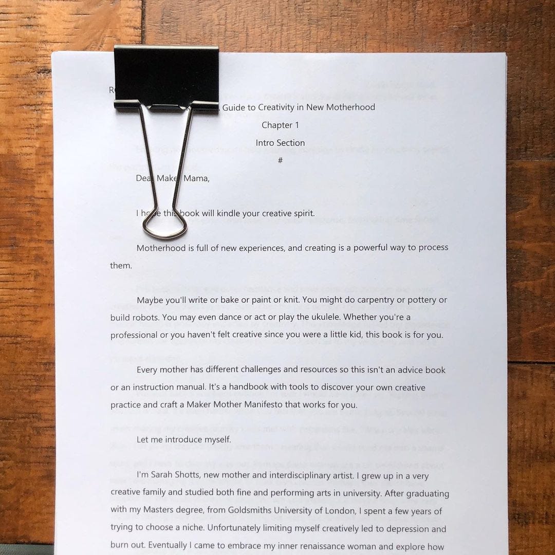 Stack of papers with giant bulldog clip, "Guide to creativity in new motherhood. Chapter 1"