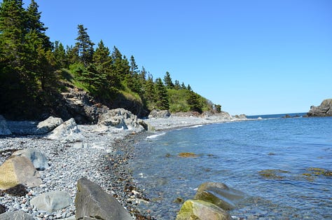 Lighthouse in Maine with rocky beaches and children playing.