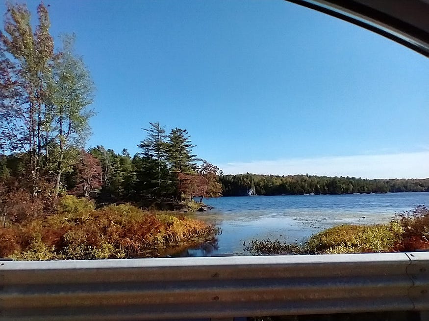 A white rock formation on the far shore of Upper Rock Lake, as seen from Opinicon Road. Blue skies and fall colours.