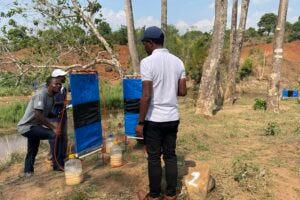 The research team in Malawi check one of the traps. The plastic containers hold a yeast and sugar solution which produces carbon dioxide, mimicking human breath.