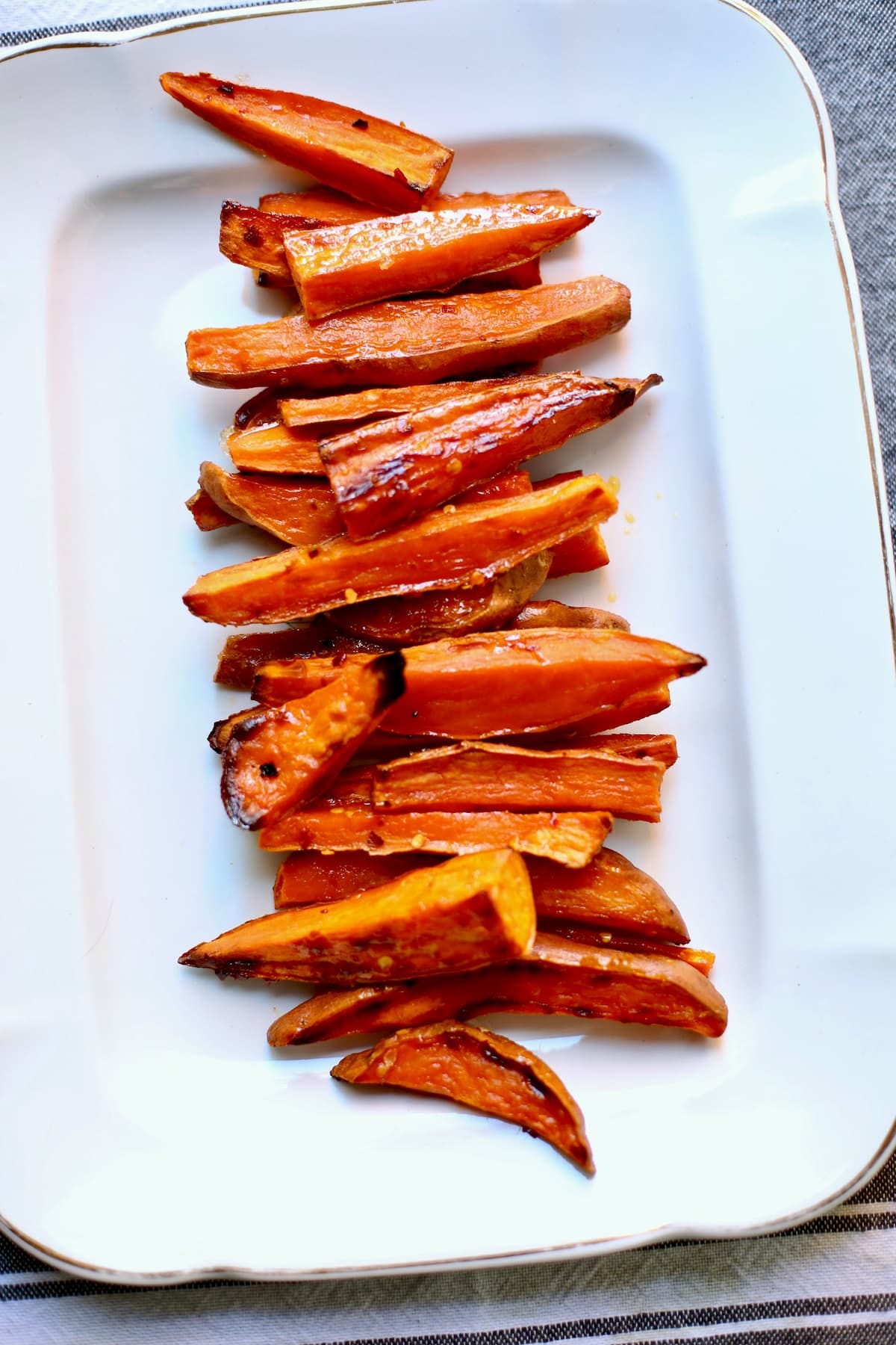 a white tray of roasted sweet potatoes.