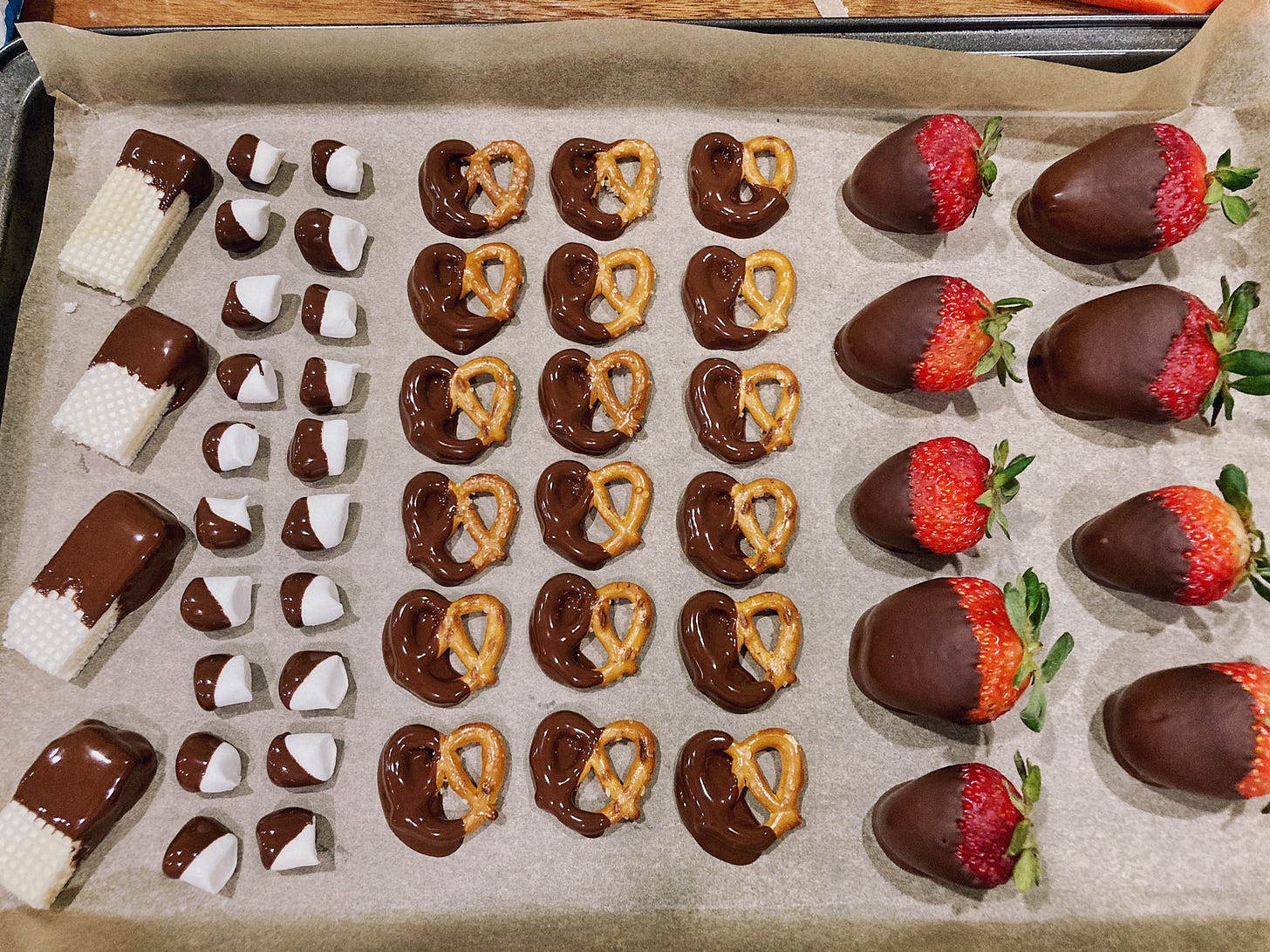 Tray with chocolate covered wafer cookies, marshmallows, pretzels, and strawberries.