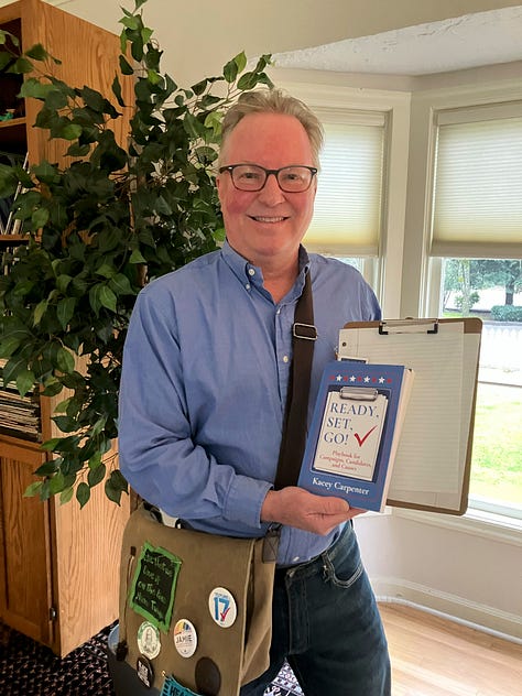 My Journey with Bernie book cover, READY, SET, GO! Playbook for Campaigns, Candidates, and Causes book cover, Kacey Carpenter author, organizer and activist holding a book, clipboard, and wearing an organizing bag with buttons
