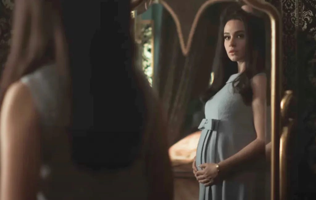 Priscilla pregnant and looking in a mirror.