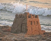 A sandcastle on a beach with the tide coming in.