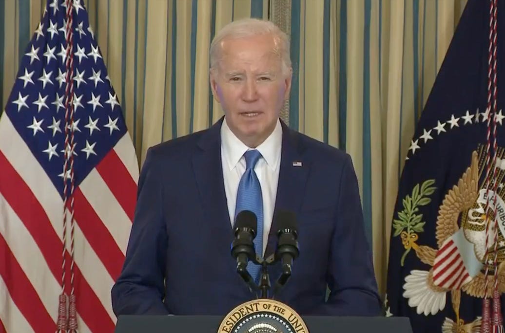 A person standing at a podium with microphones and flags behind him

Description automatically generated