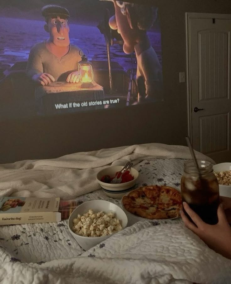 This contains: #movienight #bedroom #bedroomideas #summervibes #summernights #summer #europe #aesthetic #disney #disneyanimation #pinterest #pinterestinspired #sisters #pretty #projector #miniprojector #quilt #popcorn #kids #summeraesthetic