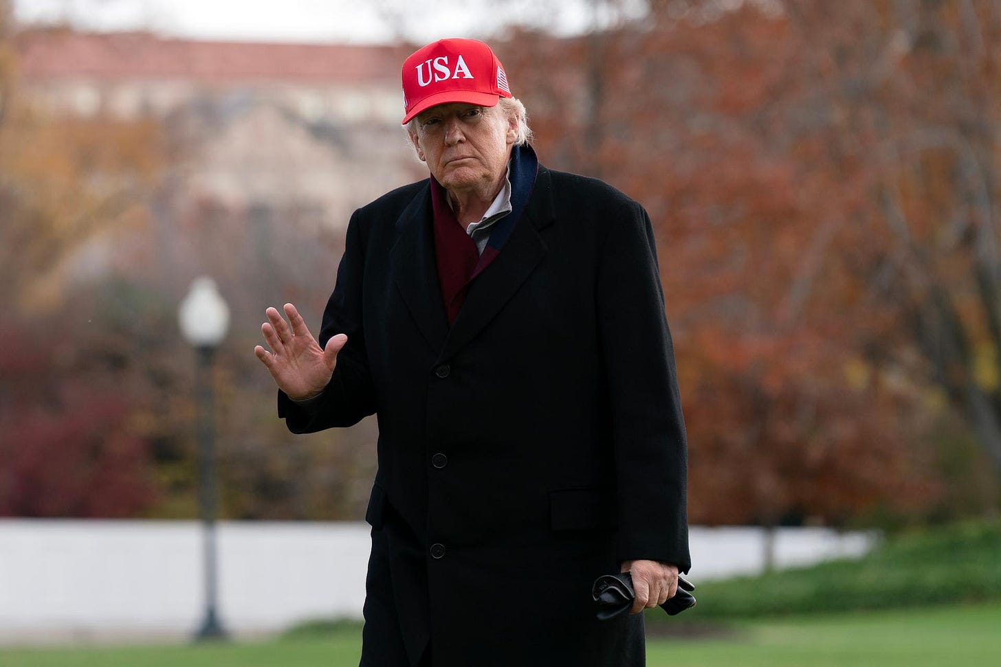 President Donald Trump waves to the media from the South Lawn upon his arrival at the White House, Saturday, in Washington.