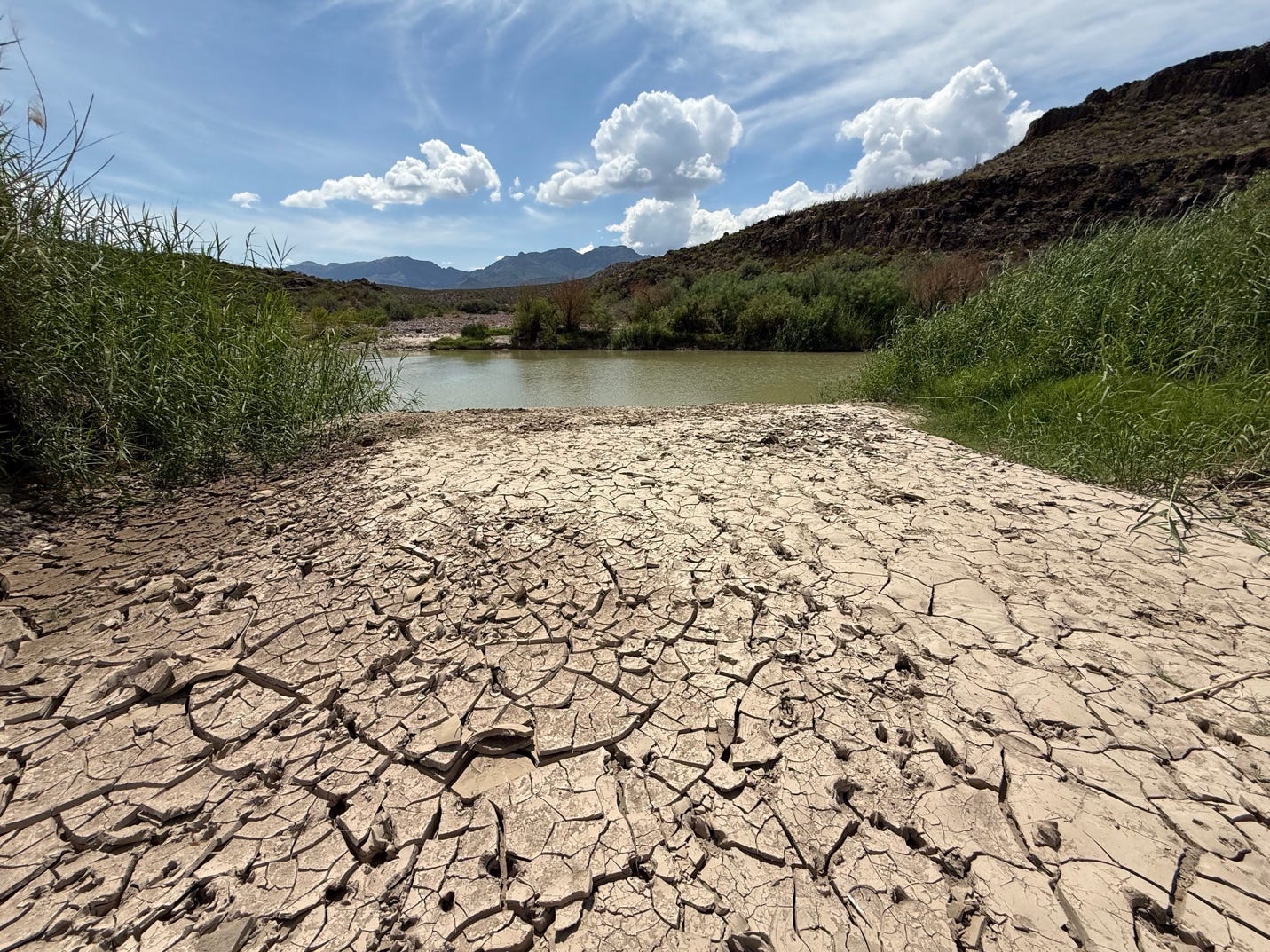 A dry cracked ground with a river in the background

AI-generated content may be incorrect.