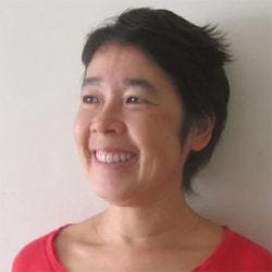 20251029_gisele-oda Mulher de cabelos curtos sorri e olha para frente. Ela usa camiseta vermelha