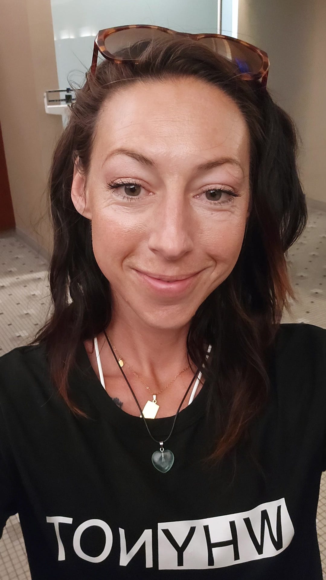 Selfie of a woman, Captain Erica, smiling at the gym wearing a "WHY NOT" t-shirt.