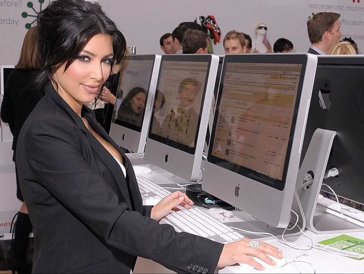 This may contain: a woman standing in front of three computer monitors