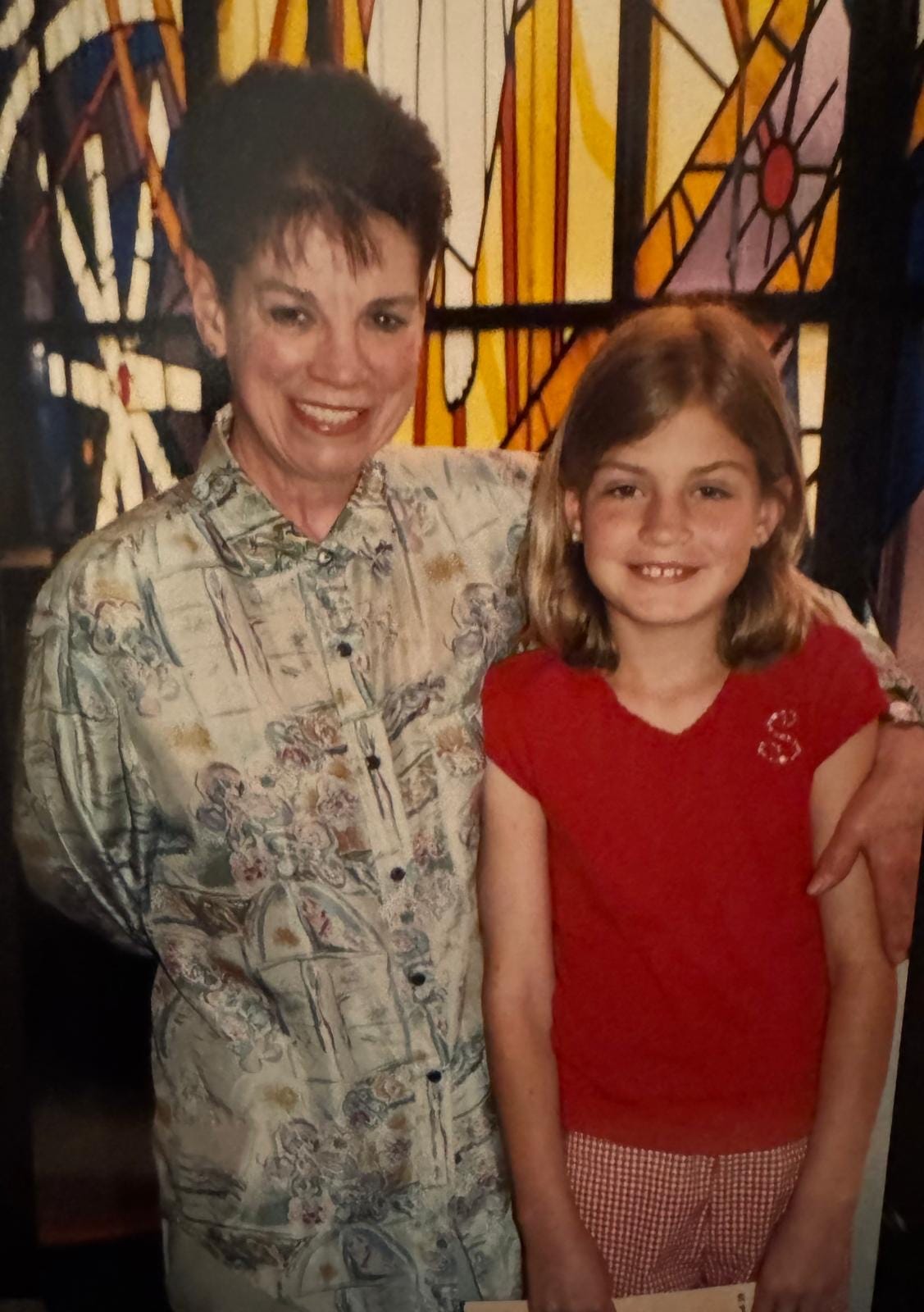 A young girl around 8 years old standing in a photo with an enthusiastic woman. They appear to be in a church at a piano recital