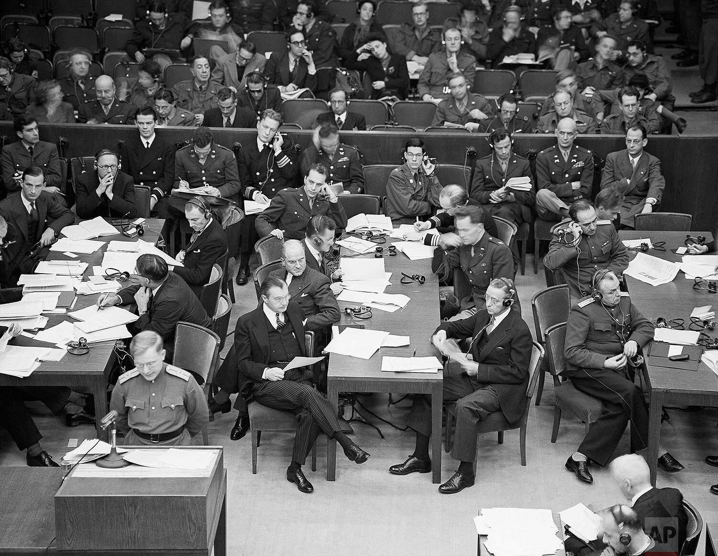 The Russian assistant prosecutor, lower left, reads the damning indictment in Nuremberg on November 28, 1945. American chief prosecutor Justice Robert Jackson and his assistant are seated at the center table, representing the Allied pursuit of justice. The Russian assistant prosecutor, lower left, reads the damning indictment in Nuremberg on November 28, 1945. American chief prosecutor Justice Robert Jackson and his assistant are seated at the center table, representing the Allied pursuit of justice.