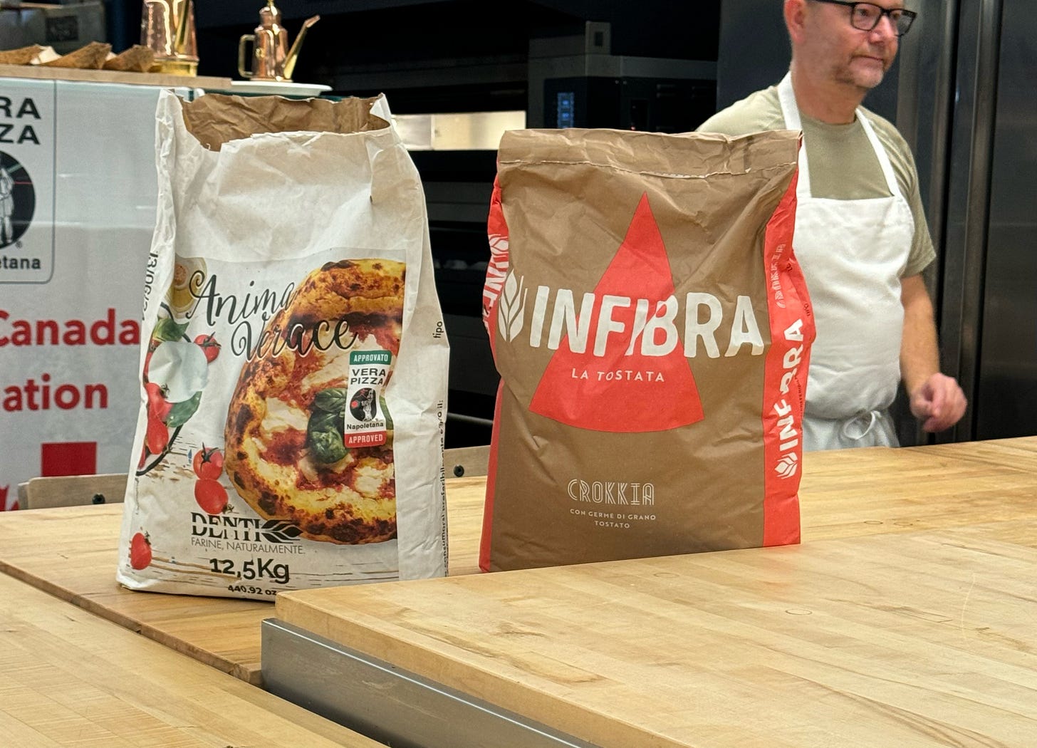 Two 12.5 kg bags of flour on a wooden counter. 