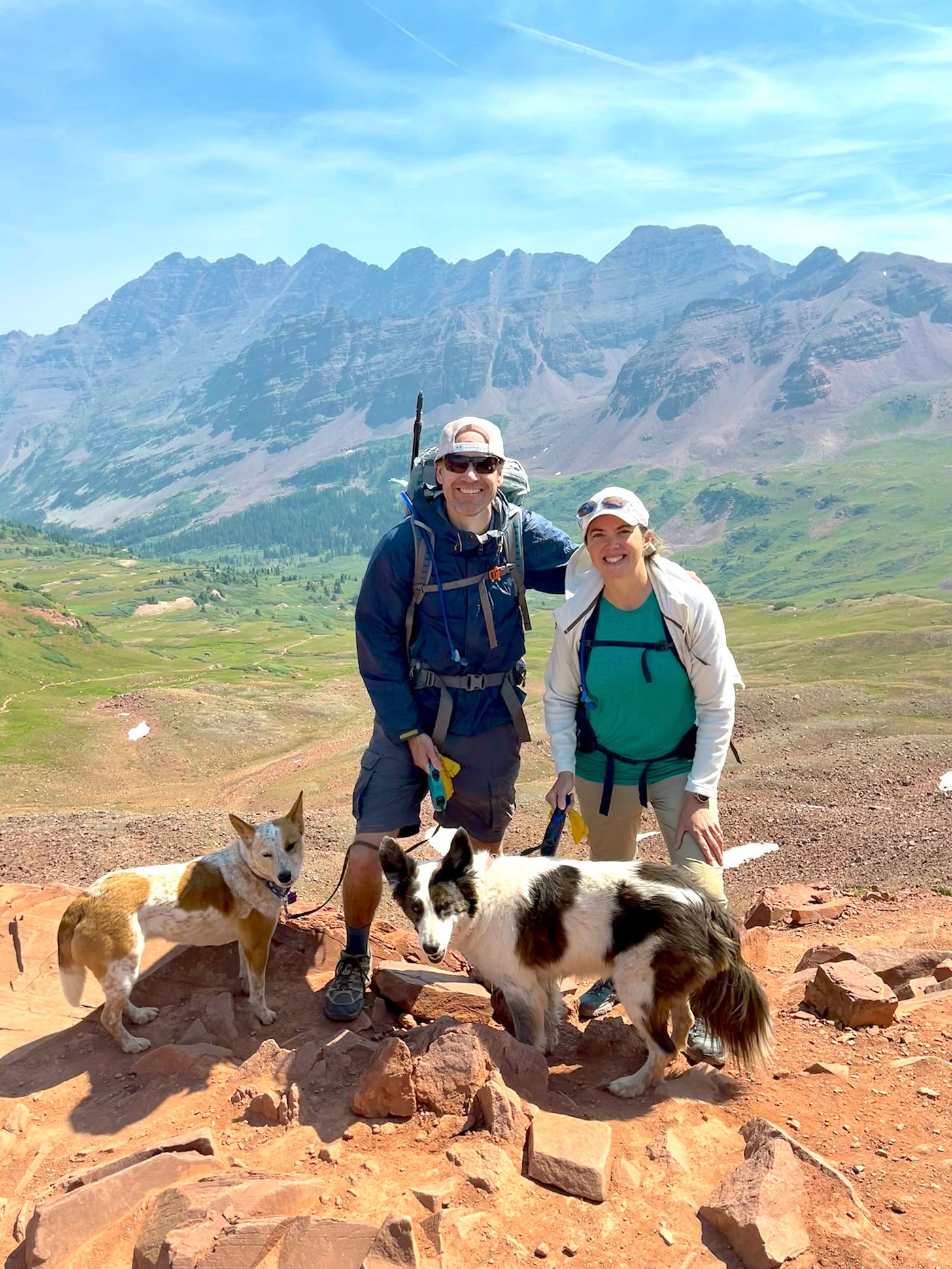 two dogs, a man and a woman standing on the summit of west maroon pass two dogs, a man and a woman standing on the summit of west maroon pass