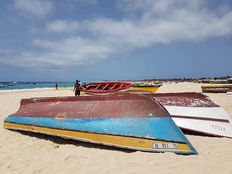 A wooden pier stretching into bright turquoise water, with small waves rolling toward the shore under a clear sky.