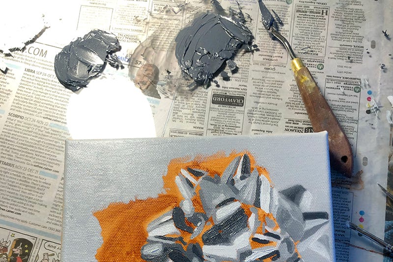A paining with grey and orange paint on newspaper.