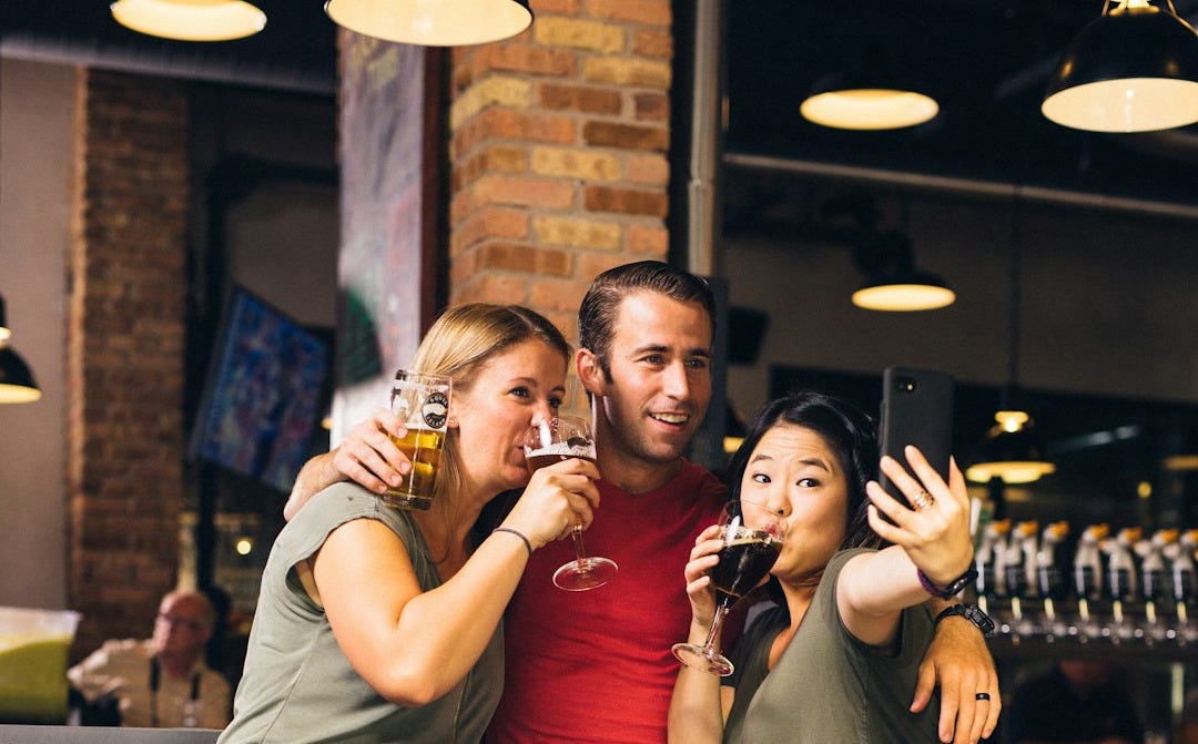 man between two women taking selfie