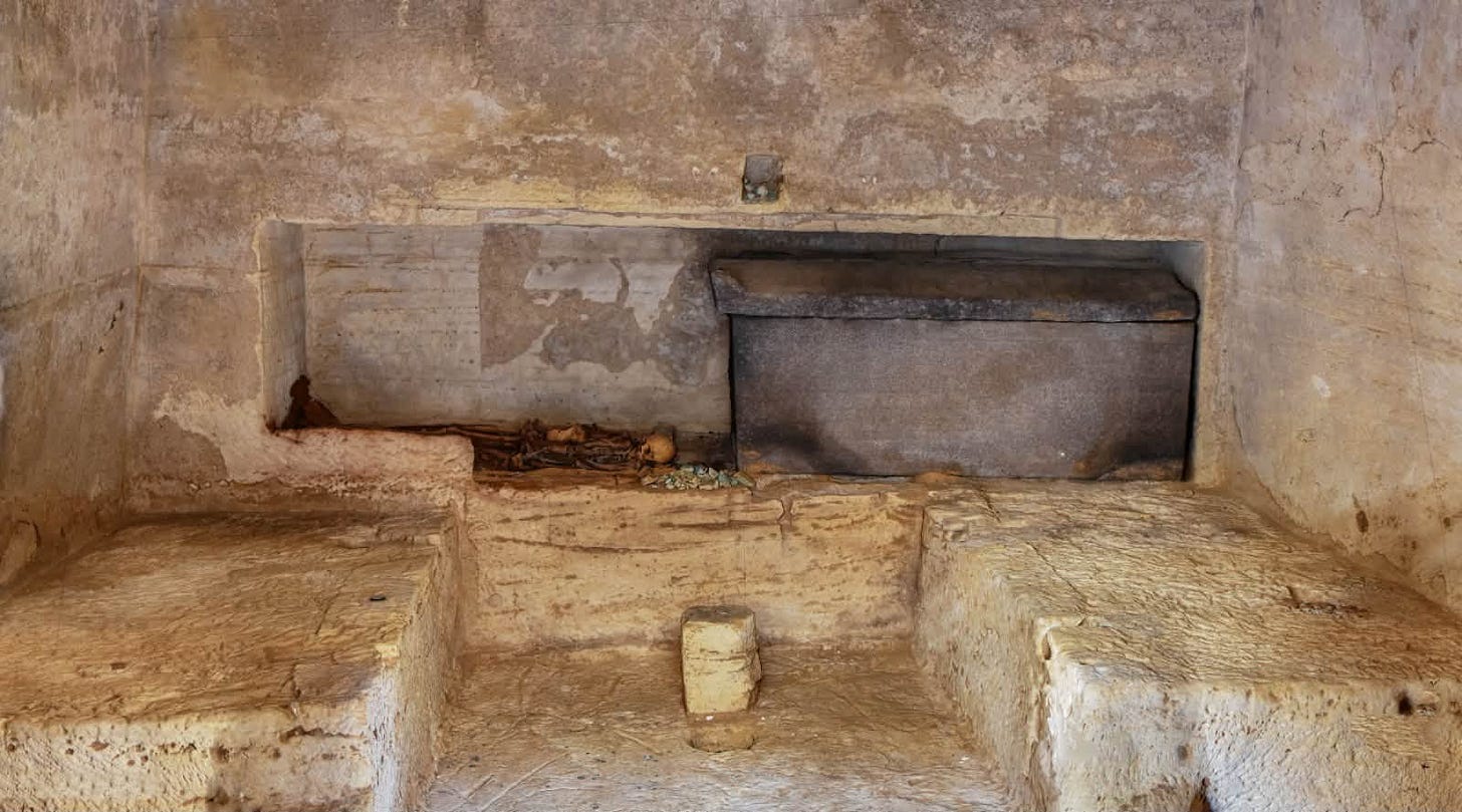 The interior of one of the rock-cut tombs uncovered at Marina El Alamein, showing a sealed sarcophagus and skeletal remains within a burial niche