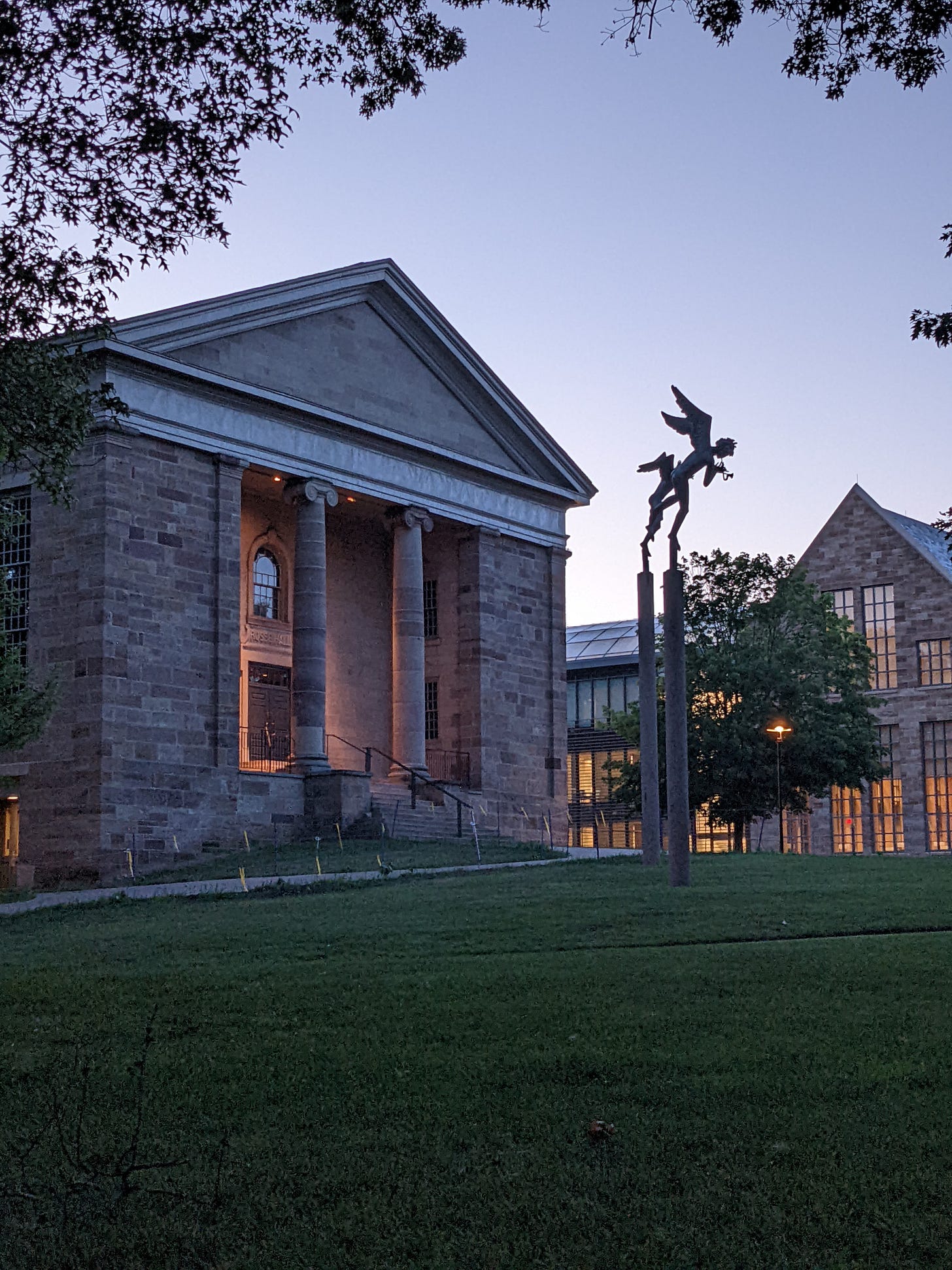 A building fronted by Ionic columns and several sculptures of angels playing instruments. 