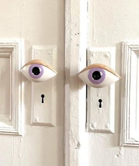 This may contain: the door is painted white and has two fake eyes on it, as well as a keyhole