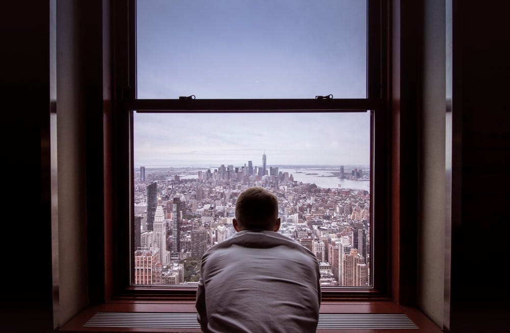 man in gray shirt looking at city buildings during daytime man in gray shirt looking at city buildings during daytime