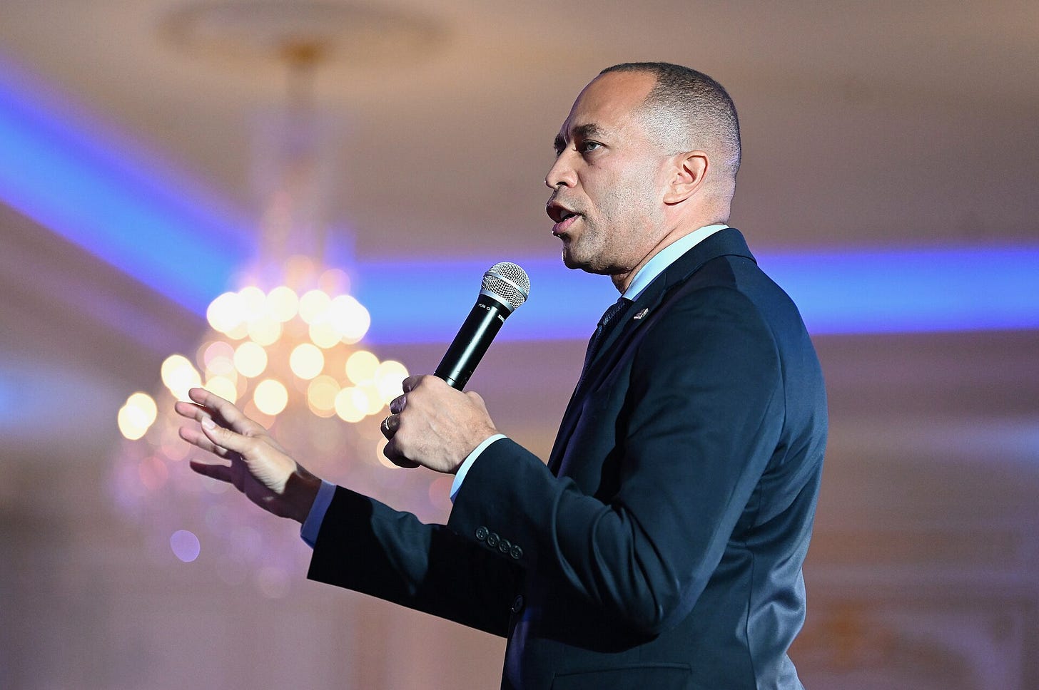 Hakeem Jeffriees speaking into microphone and gesturing wearing suit; he is turned to the side Hakeem Jeffriees speaking into microphone and gesturing wearing suit; he is turned to the side
