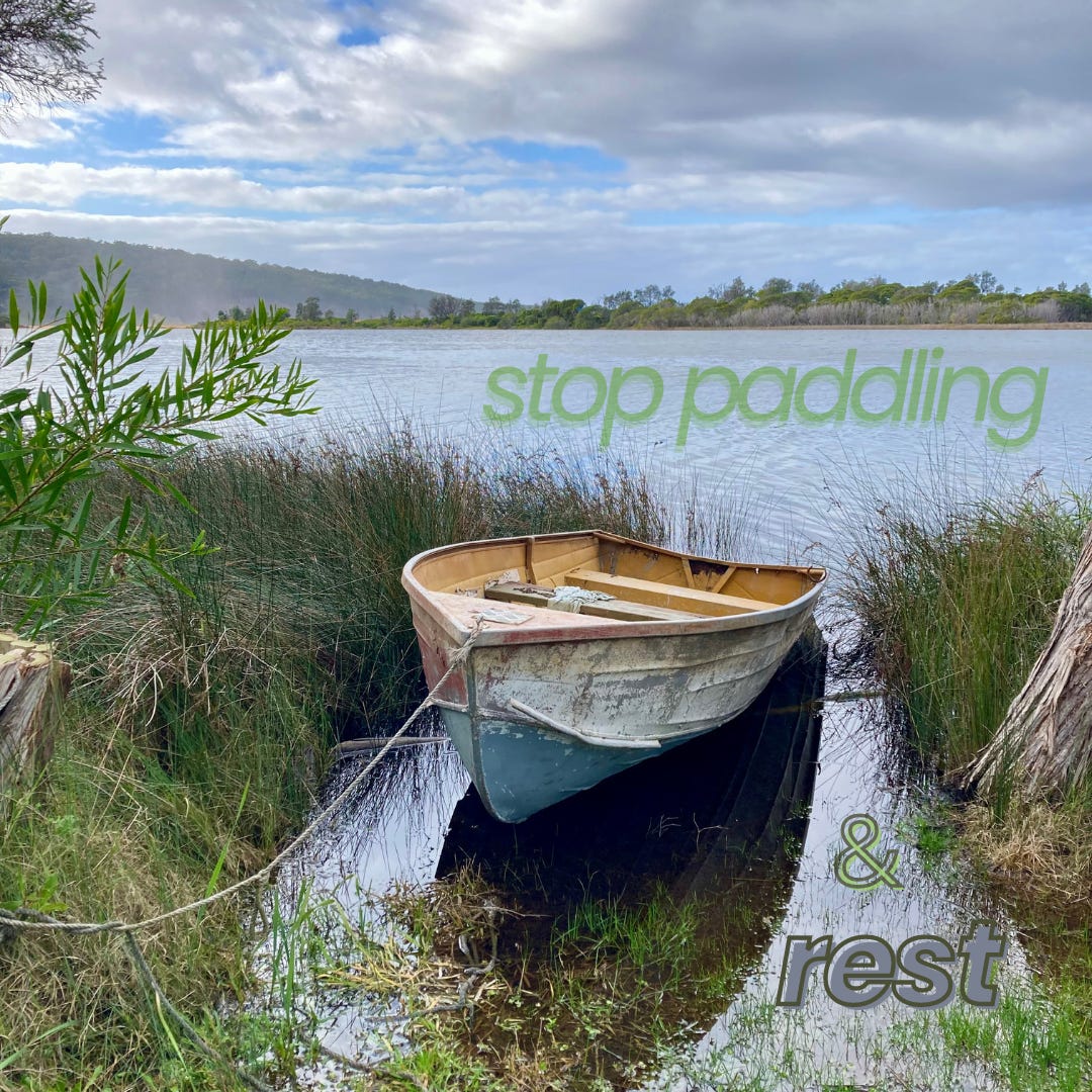 Row boat moored in reeds at edge of lake. "Stop paddling and rest."