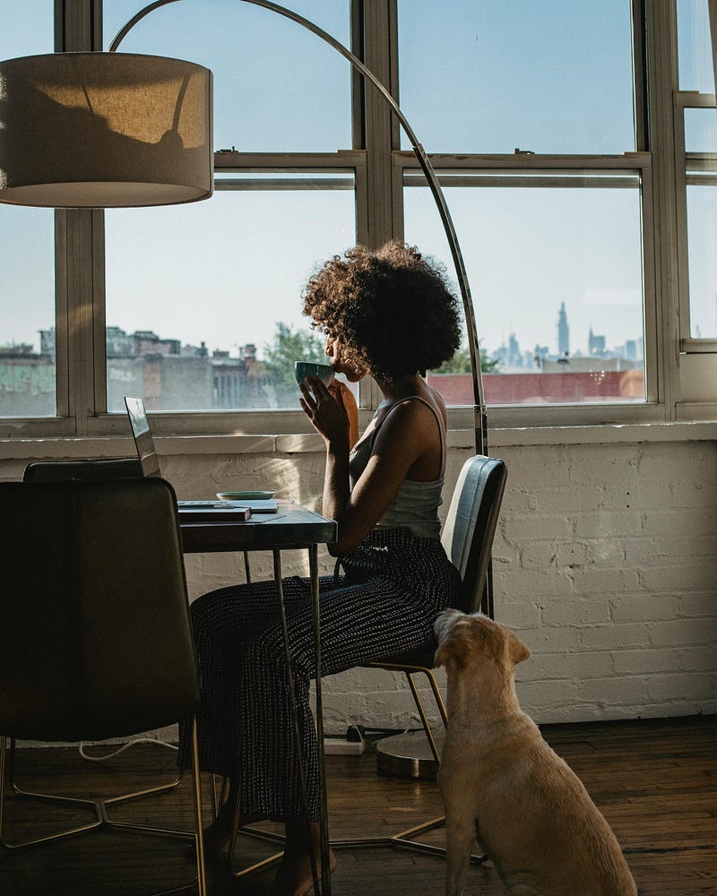 A woman sitting in front of her laptop, drinking tea.