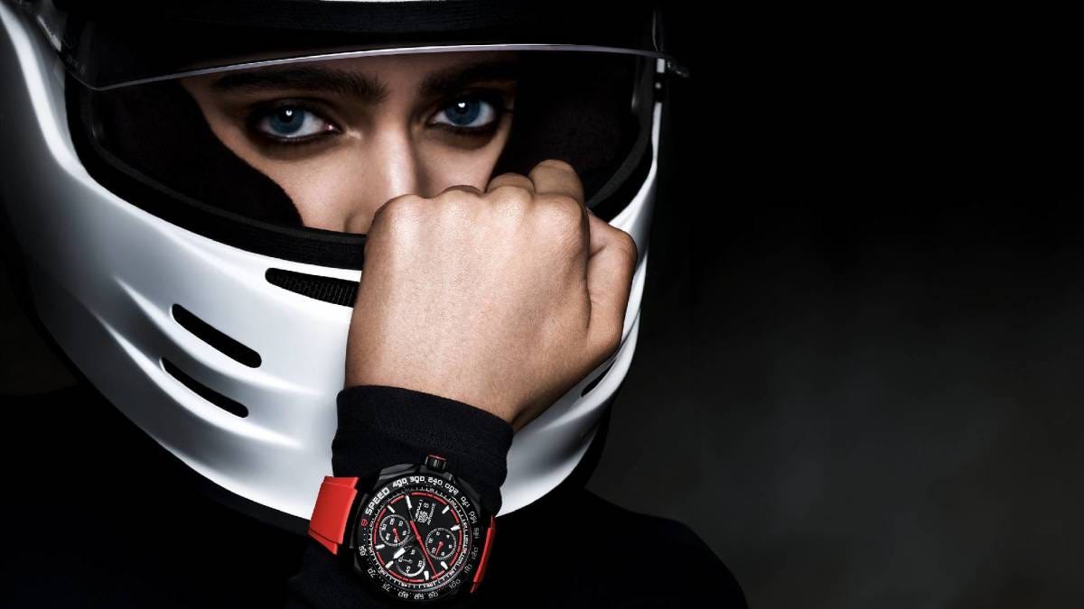 Woman wearing a white race car helmet with a TAG Heuer Formula 1 Chronograph Watch on her wrist on a black background, new watch release.