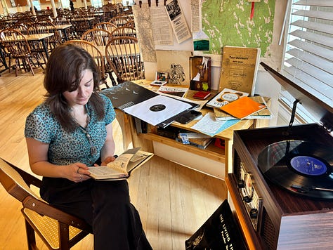 FROM TOP LEFT: BB loading flats into the Bread Loaf barn; row of trees on Bread Loaf campus; mountains overlooking Ripton, VT. FROM MIDDLE LEFT: Piazza flats in Bread Loaf barn; Emma (me) setting up one of the walls for the Dorm Room environment in the Bread Loaf dining hall; BB in front of Piazza posters. FROM BOTTOM LEFT: Fionna Brennan in the Dorm Room with Paradise Now book; misc materials on Piazza cafe table in the barn; dusk on the Bread Loaf campus