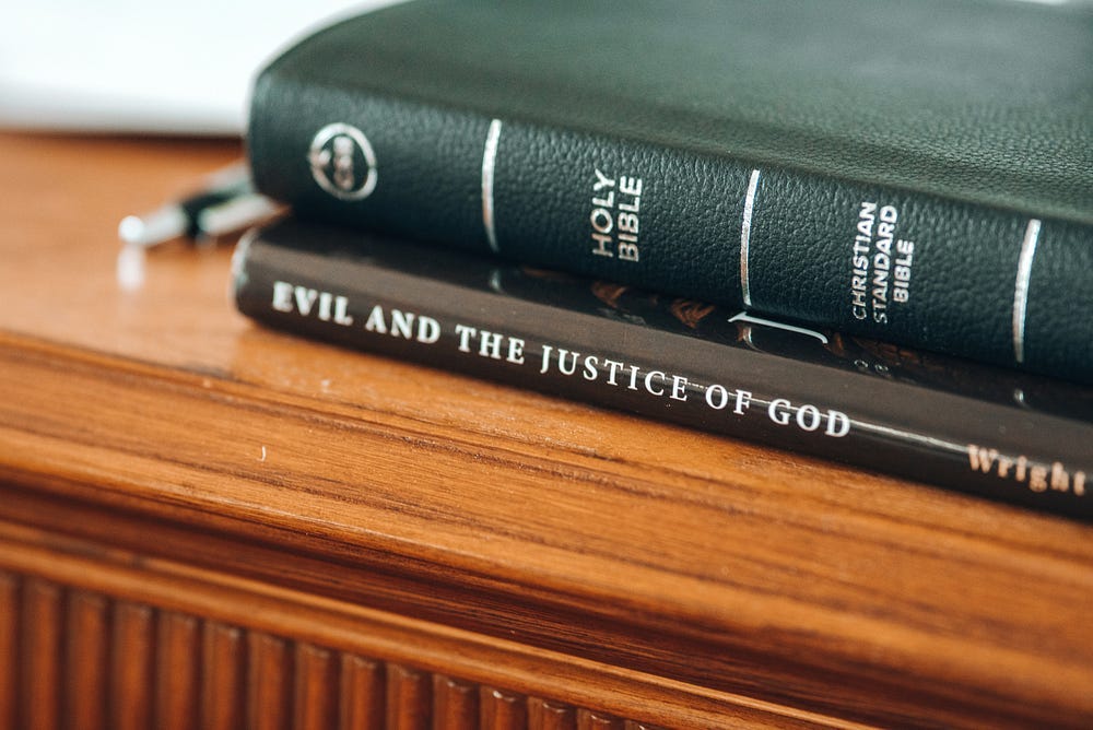 The Holy Bible resting on top of a book entitled “Evil and the Justice of God” The Holy Bible resting on top of a book entitled “Evil and the Justice of God”
